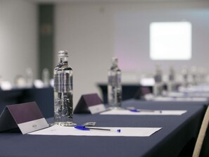 Ein Konferenzraum mit Tischen, Wasserflaschen, Namensschildern und Stiften.