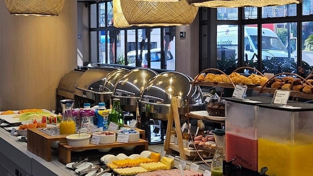 Zona de bufé con diversas opciones de comida y un interior moderno con lámparas colgantes de mimbre.