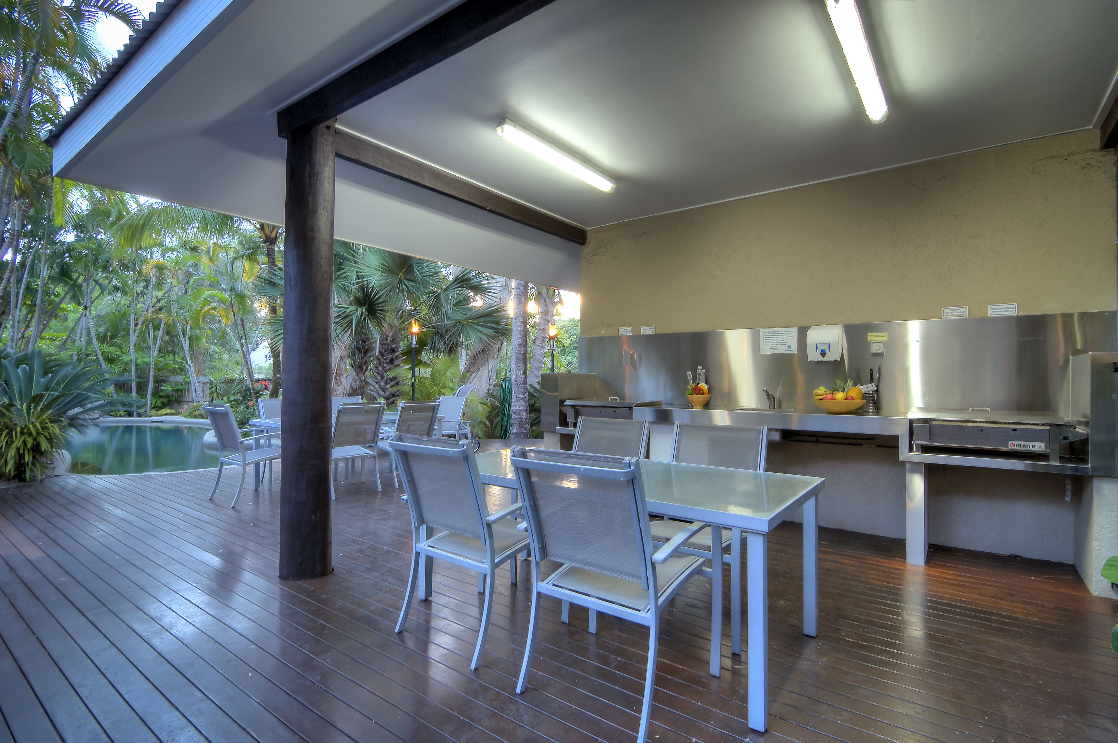 Un área de comedor al aire libre con piscina, sillas y una mesa.