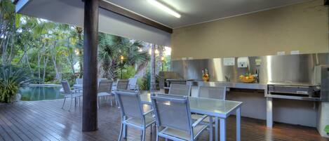 Un área de comedor al aire libre con piscina, sillas y una mesa.