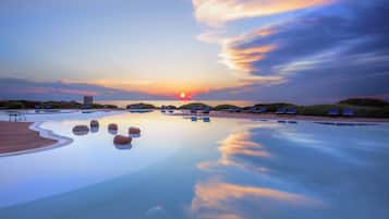 Una piscina al aire libre, sombrillas, sillones reclinables de piscina