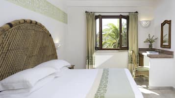 Habitación de hotel con una cama grande, una ventana con cortinas, una mesita de noche, una silla y un espejo.