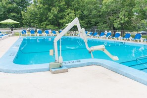 A swimming pool with blue water, surrounded by blue and white lounge chairs, and a diving board.
