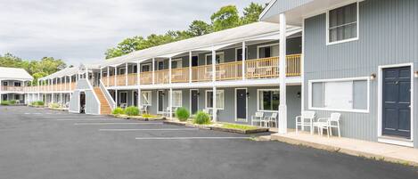 A motel with multiple-story buildings, outdoor seating, and a parking lot.