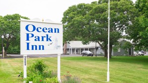 A sign for Ocean Park Inn with a clear view of the surrounding greenery and a building in the background. - Ocean Park Inn (Eastham)