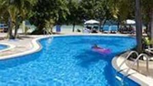 A swimming pool surrounded by palm trees and lounge chairs. - Long Bay Resort (Ko Pha-ngan)