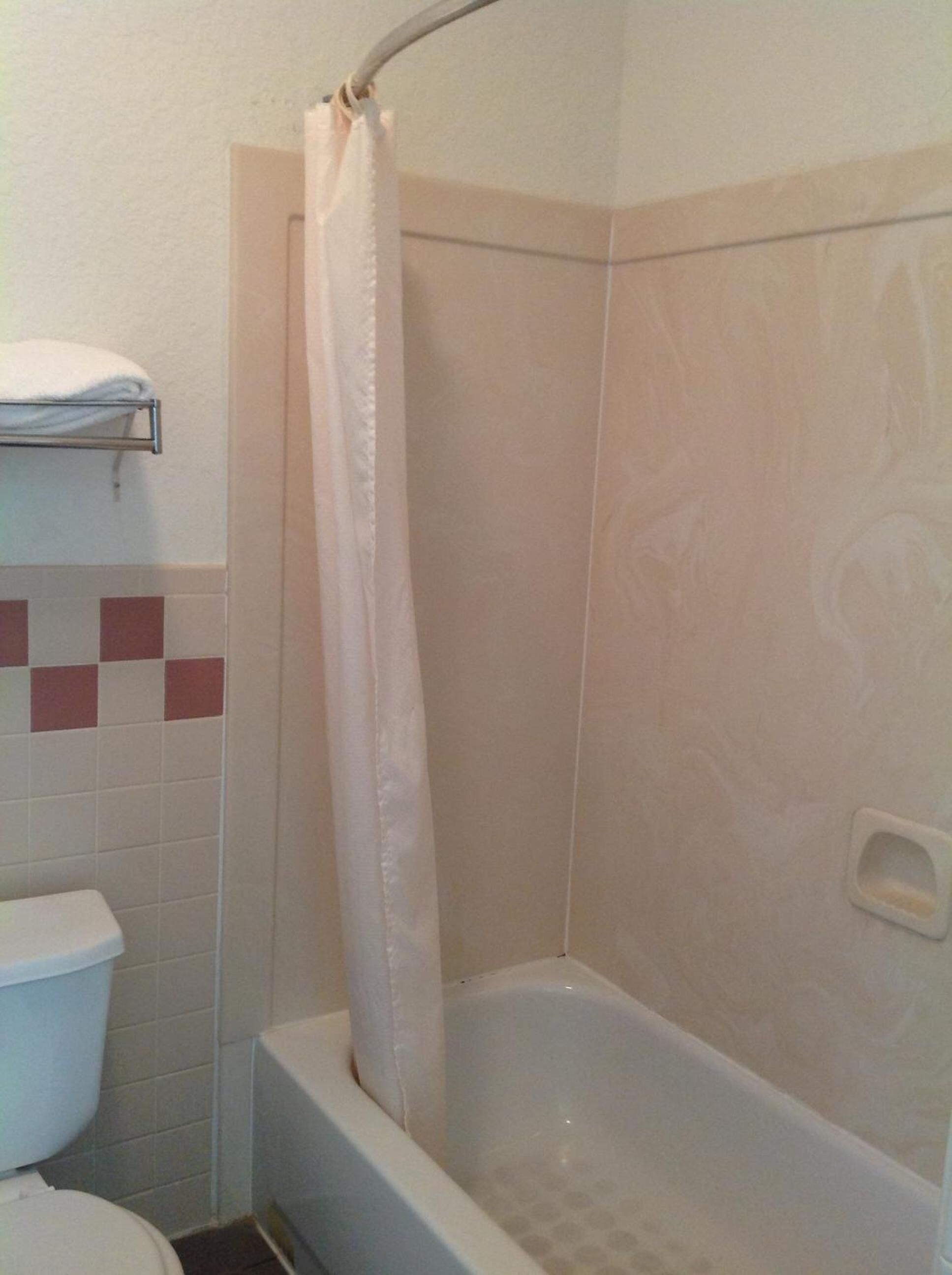 Une salle de bain avec une baignoire, des toilettes et un rideau de douche.