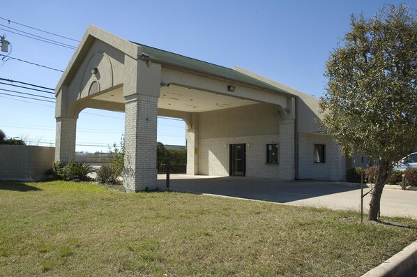 A building with a covered entrance, brick columns, and a flat roof.