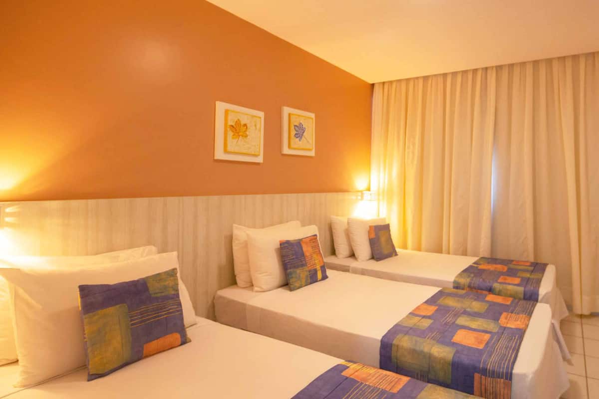 Habitación de hotel con dos camas, televisor y ventana con cortinas.
