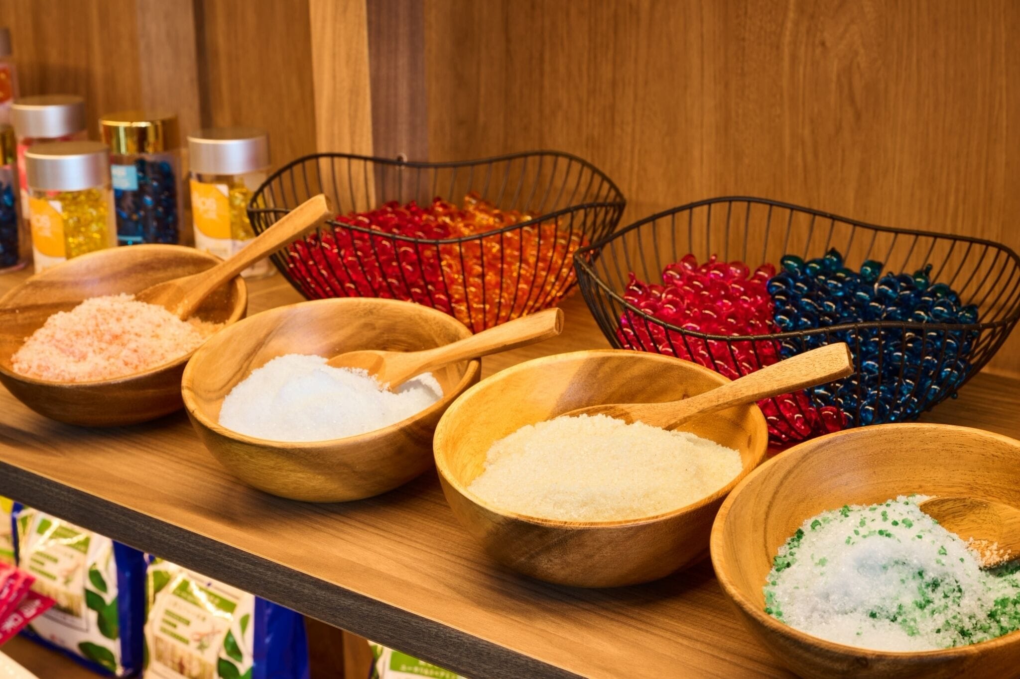 Bunte Salze und Gewürze in Holznäpfen auf einem Holzregal.