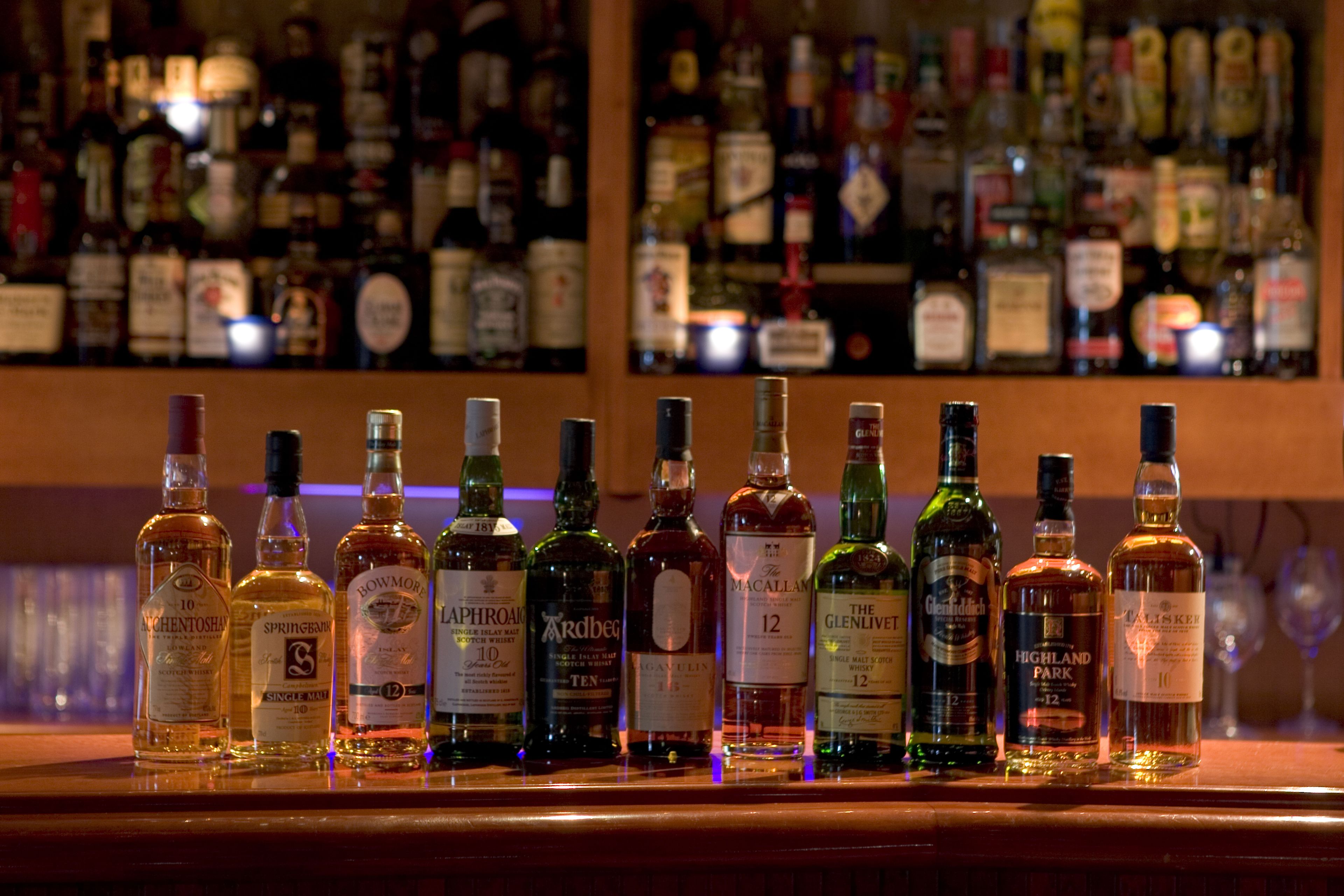 A bar with various bottles of liquor arranged on a shelf.