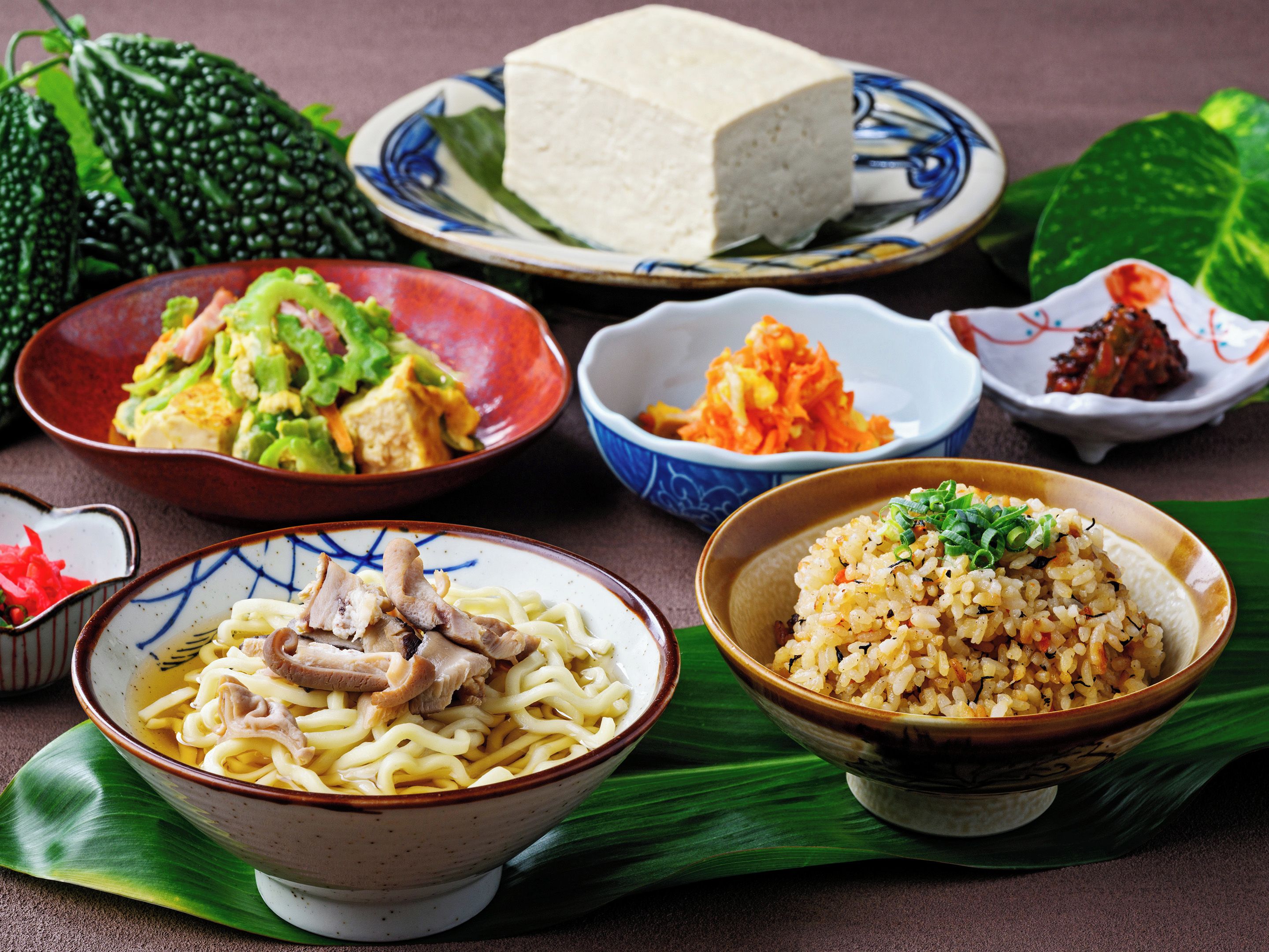 A variety of dishes including noodles, rice, and vegetables, served on traditional bowls and plates.