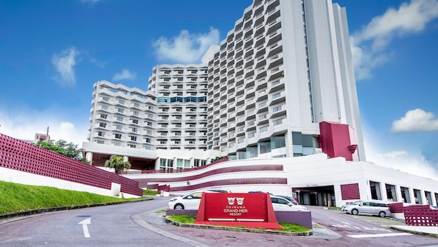 A modern hotel with a prominent entrance, multiple floors, and a red sign indicating the name. - Okinawa Grand Mer Resort (Okinawa)