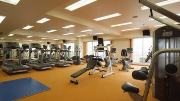 Un gimnasio con cintas de correr, una banca y diferentes máquinas de ejercicio.
