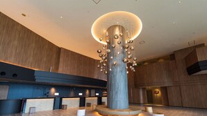 A spacious lobby with a central column, wooden accents, and a modern chandelier. - Okinawa Grand Mer Resort (Okinawa)