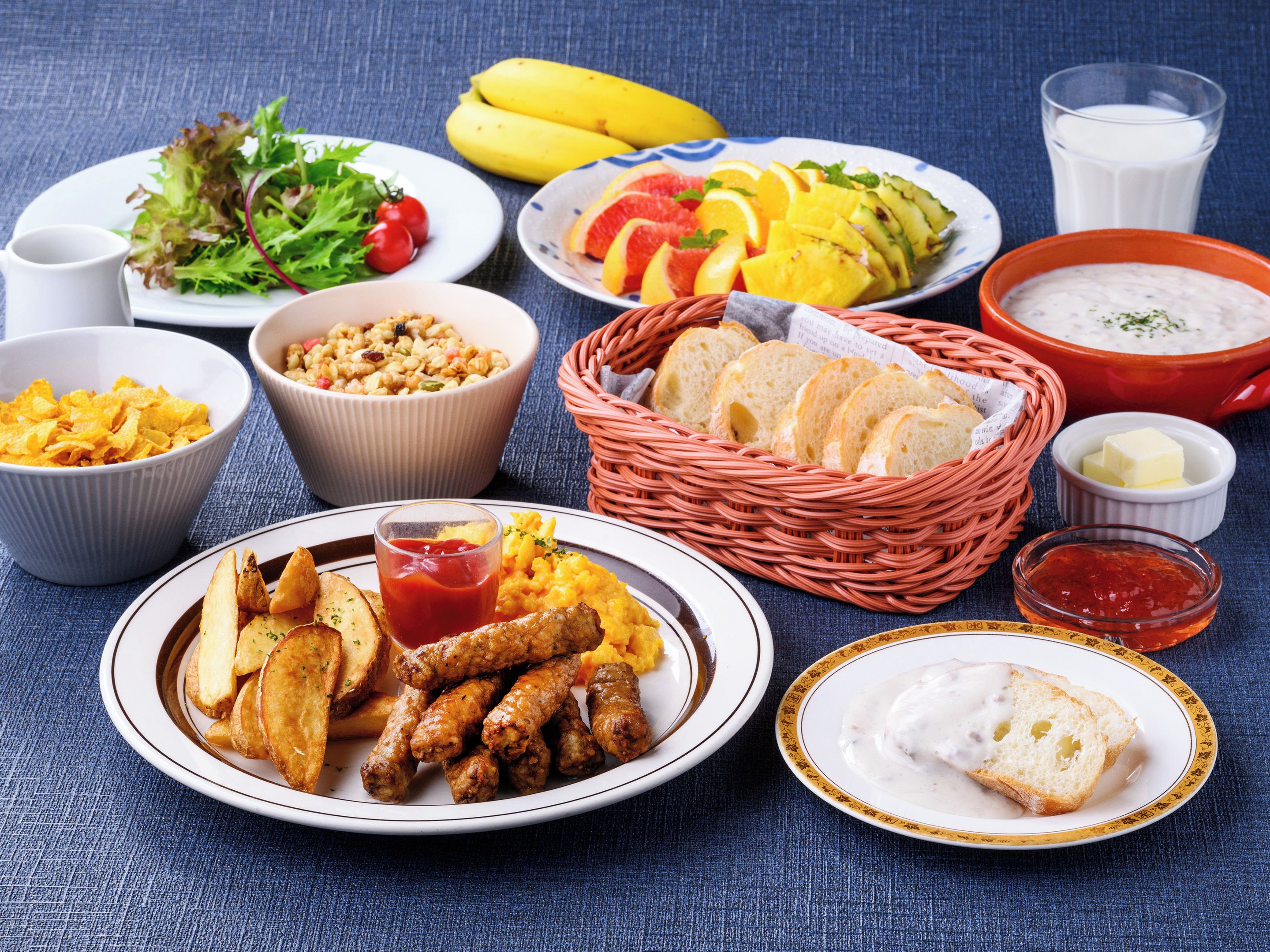 A variety of food items including a plate of fried chicken, a bowl of soup, and a basket of bread.