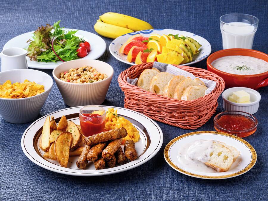 Variedad de alimentos, entre ellos, un plato de pollo frito, un tazón de sopa y una cesta de pan.