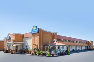 A Days Inn & Suites building with a red roof, multiple rooms, and a welcoming entrance with potted plants.
