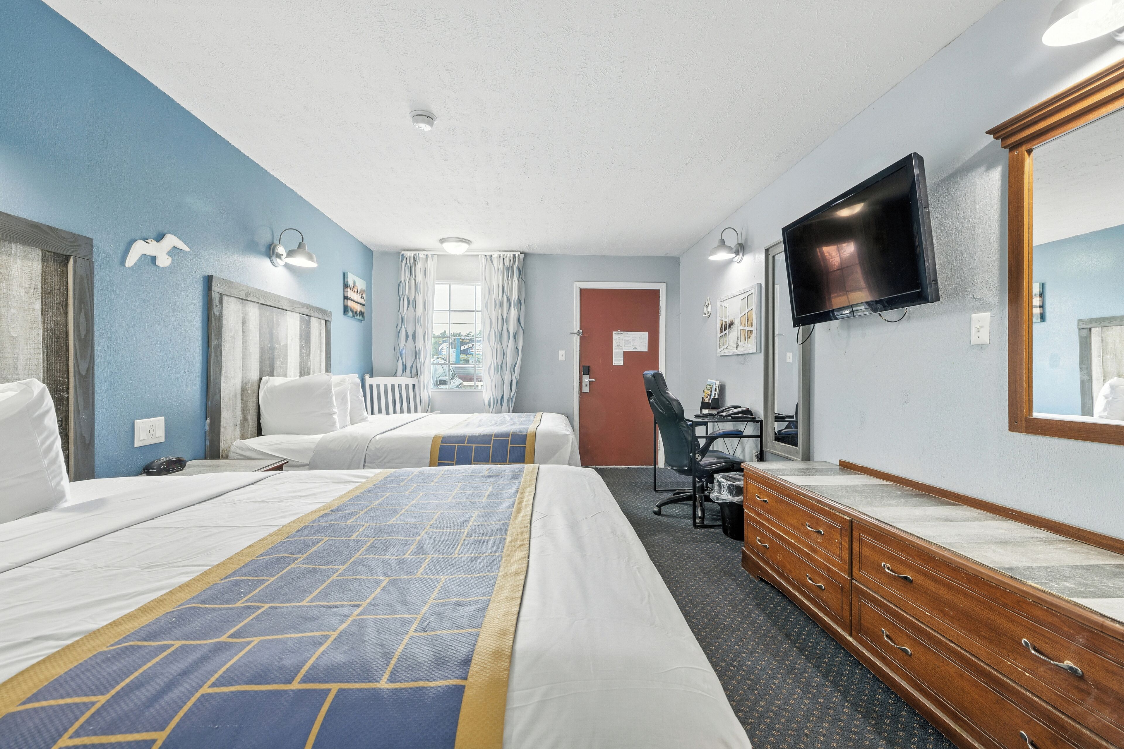 Une chambre d’hôtel avec deux lits, un bureau, une chaise, une commode et un téléviseur.