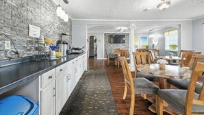 Una cocina con salpicadero de ladrillo, mesa de comedor de madera y sillas.