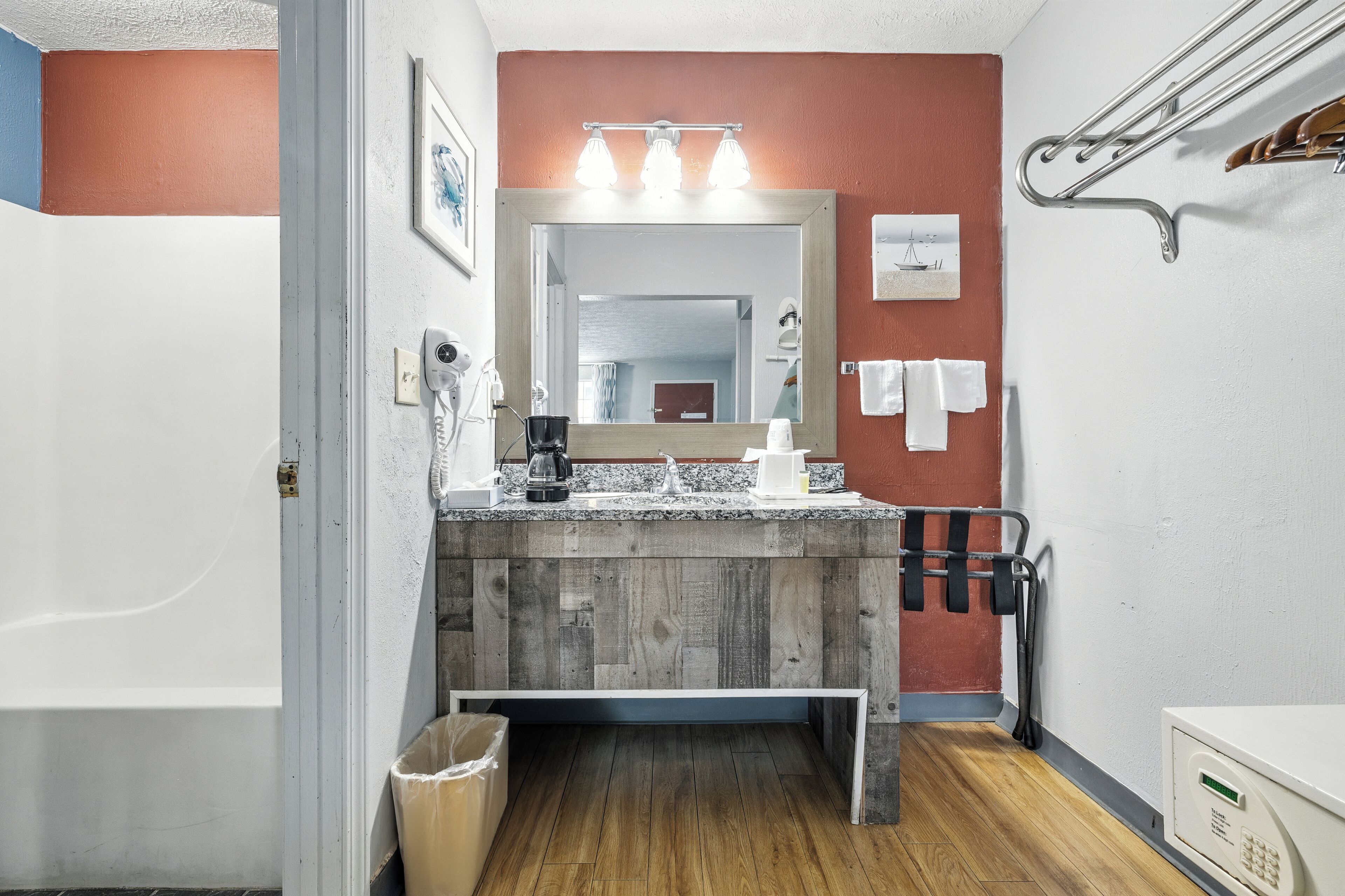 Un baño con tocador de madera, un espejo grande, toallero y zona de ducha.
