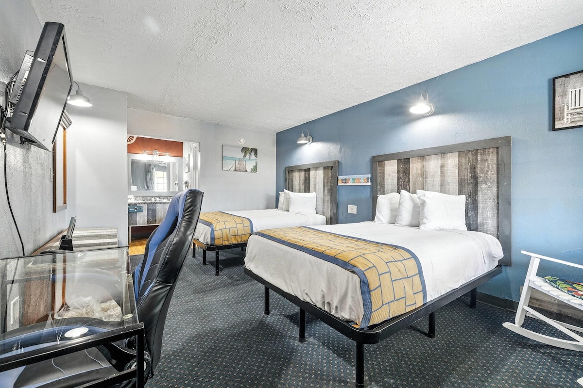 A hotel room with two beds, a desk with a computer, and a mirror.