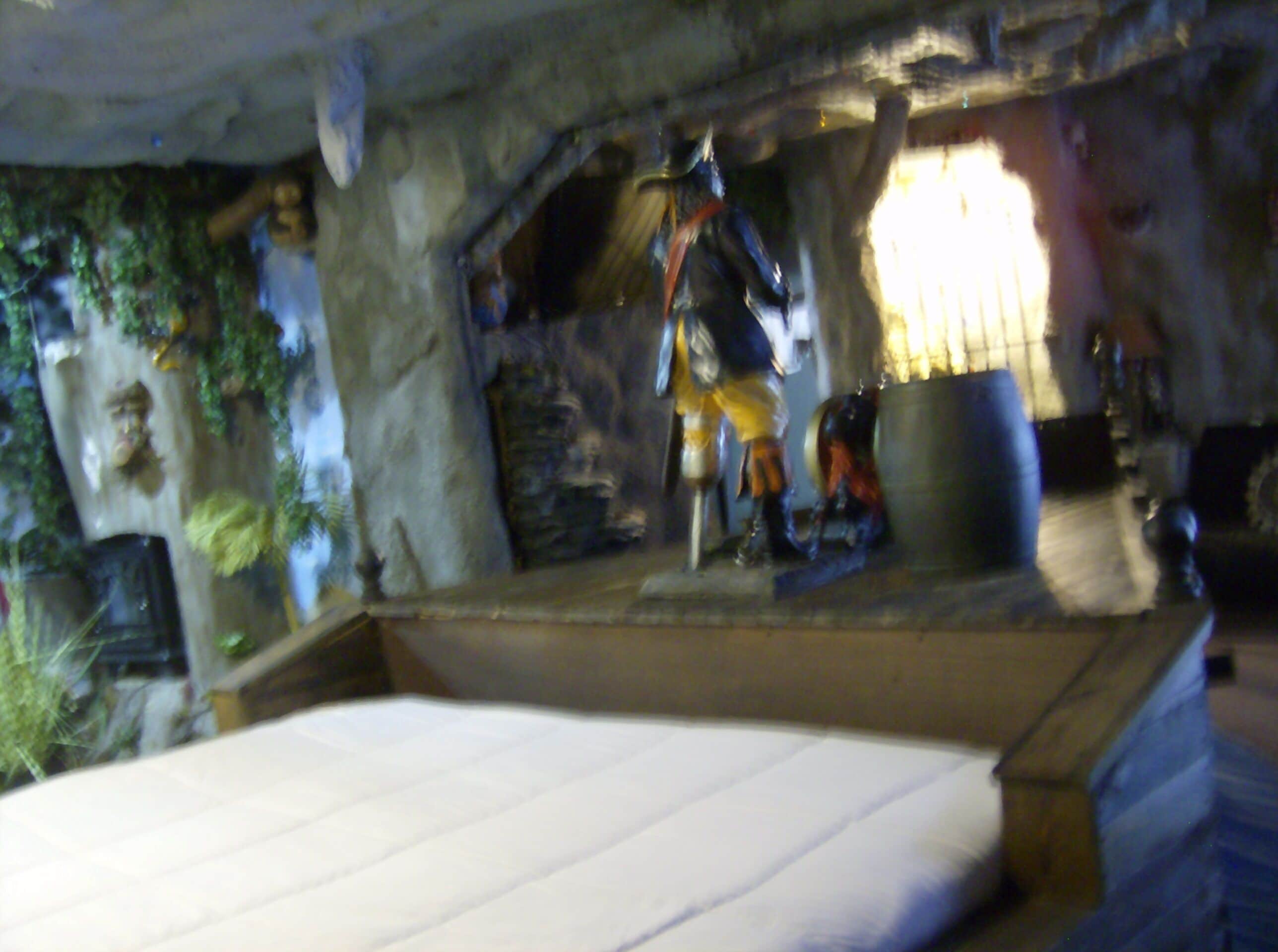 Una habitación con una cama, un muro de piedra y una estatua.