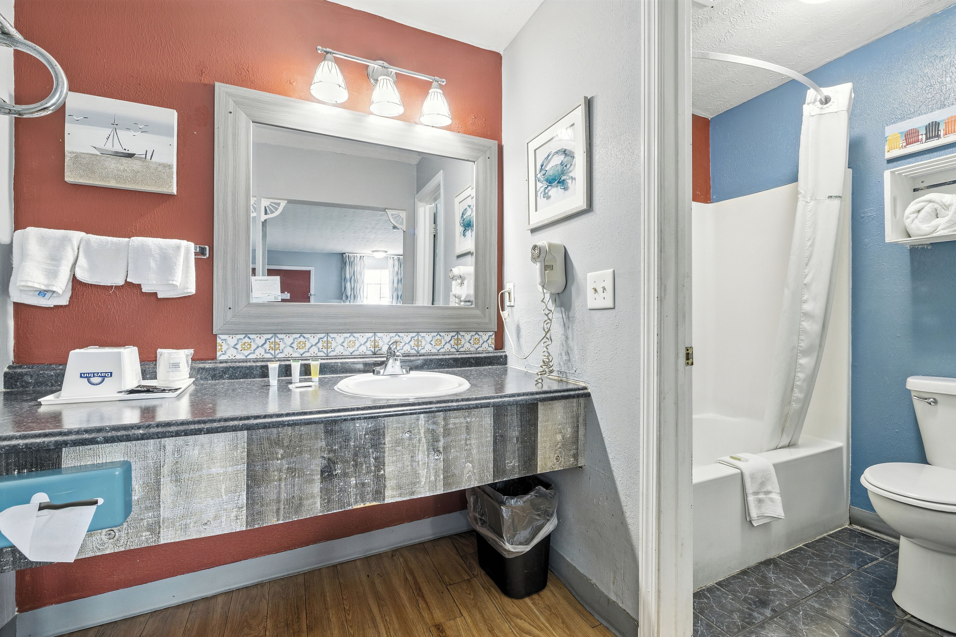 Un bagno con un lavandino in marmo, uno specchio, un asciugacapelli e una tenda per la doccia.