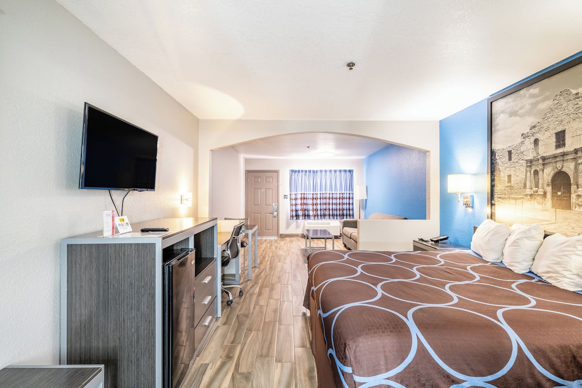 Ein Hotelzimmer mit Bett, Schreibtisch, Stuhl, Fernseher und Blick auf ein Gebäude durch ein Fenster.