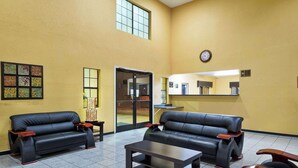 A lobby with two black leather sofas, a coffee table, and a tiled floor.