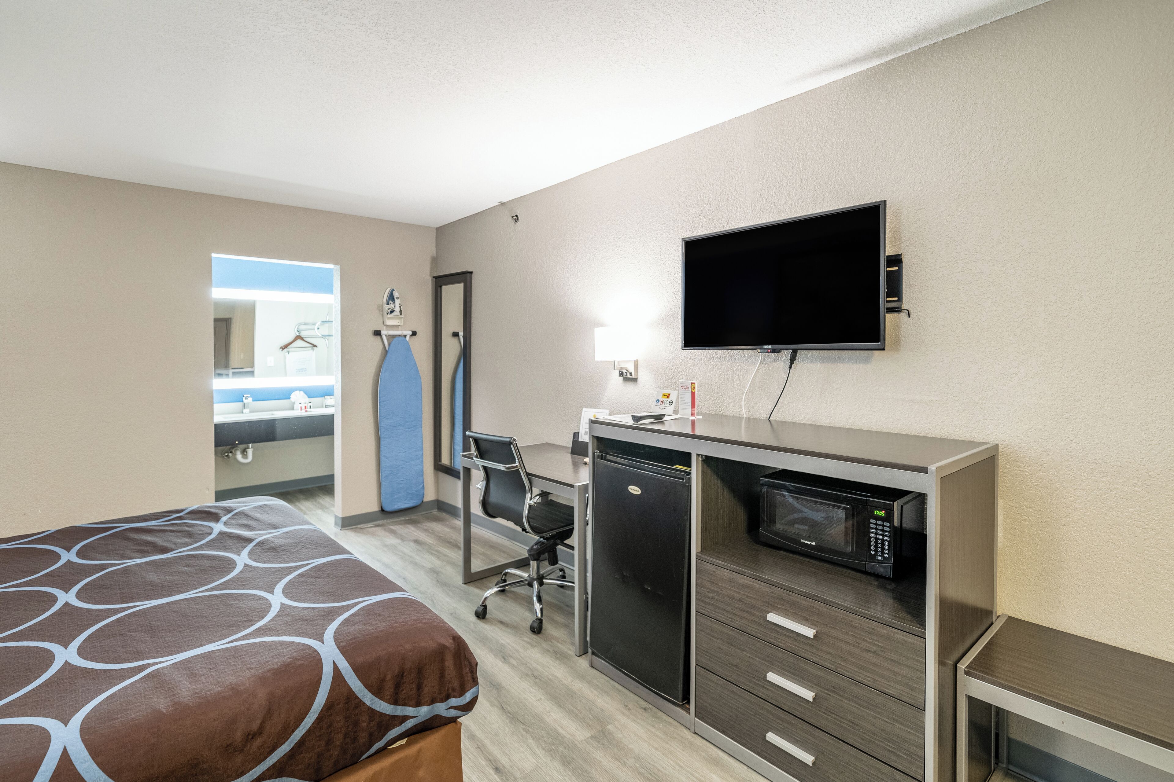 Une chambre d’hôtel équipée d’un lit, d’un bureau, d’un four à micro-ondes et d’une télévision.