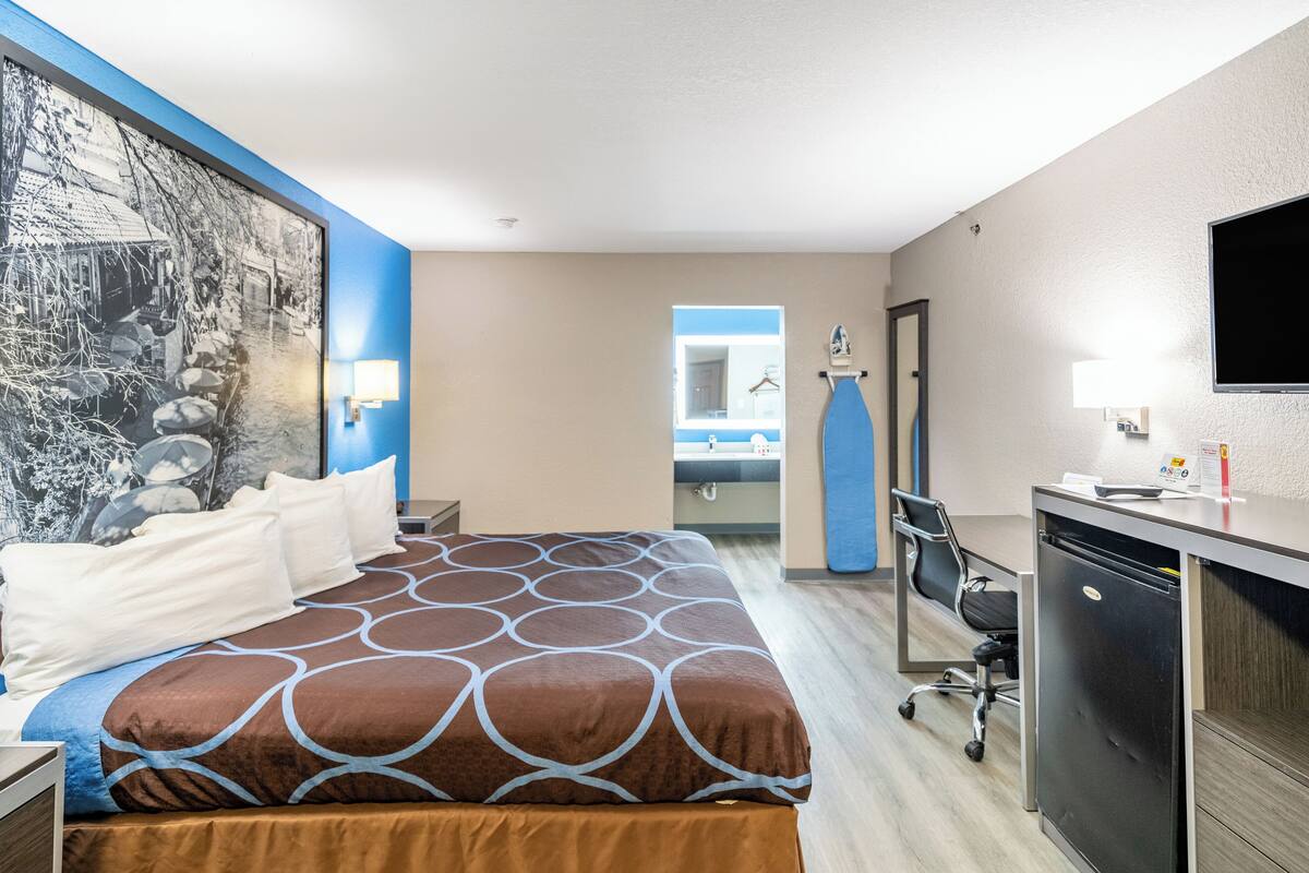 Ein Hotelzimmer mit Bett, Schreibtisch und Fernseher.