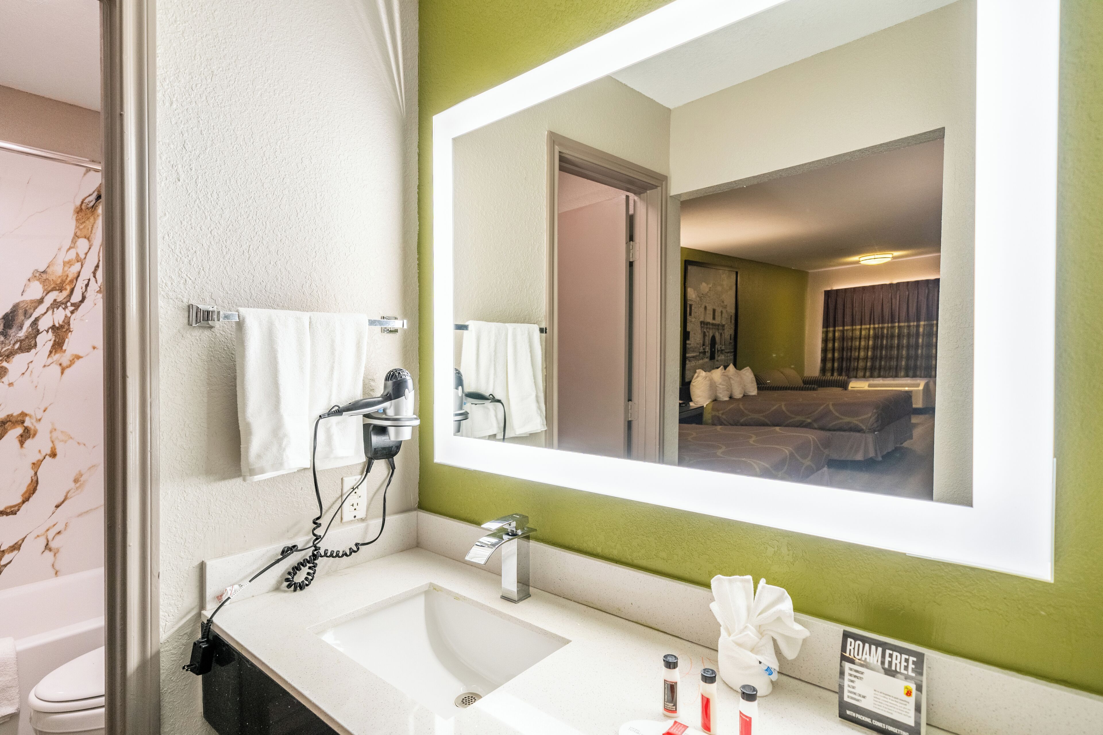 Un baño con lavamanos blanco, un espejo y un perchero para toallas.