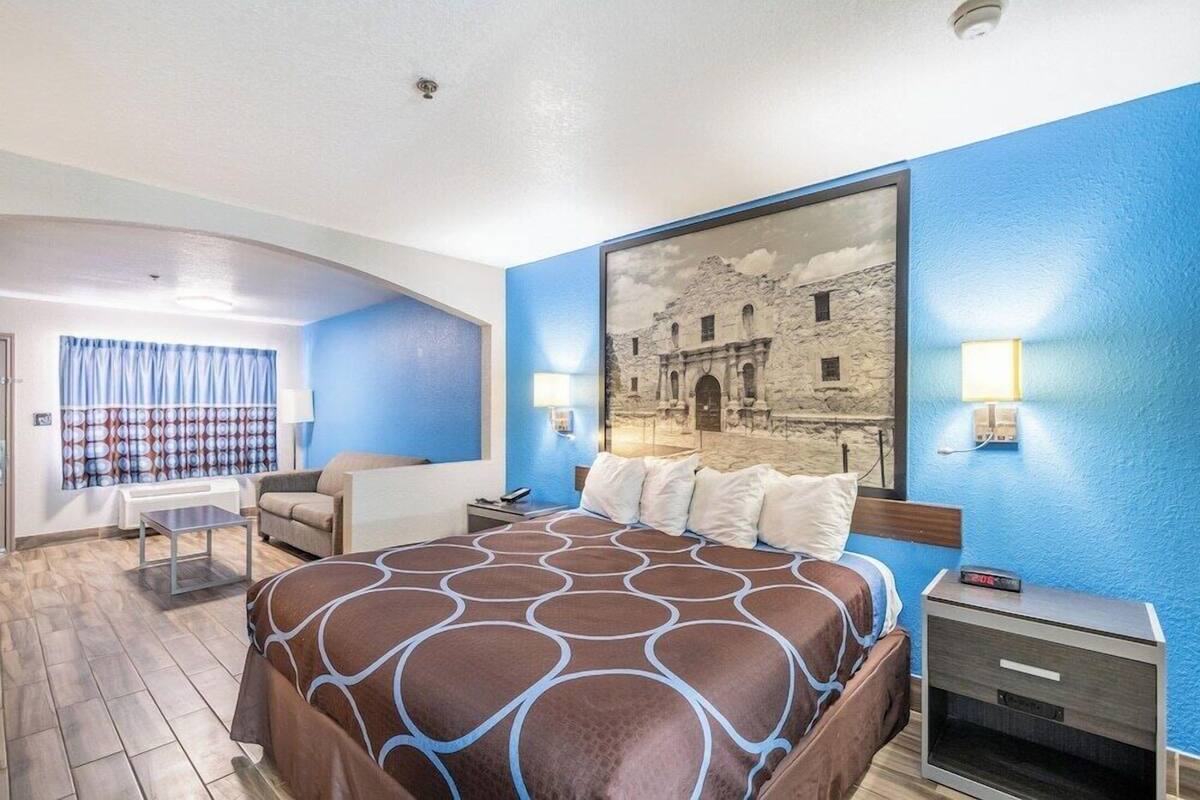 Ein Hotelzimmer mit einem Bett, einem Schreibtisch, einem Sessel und einem Wandbild.