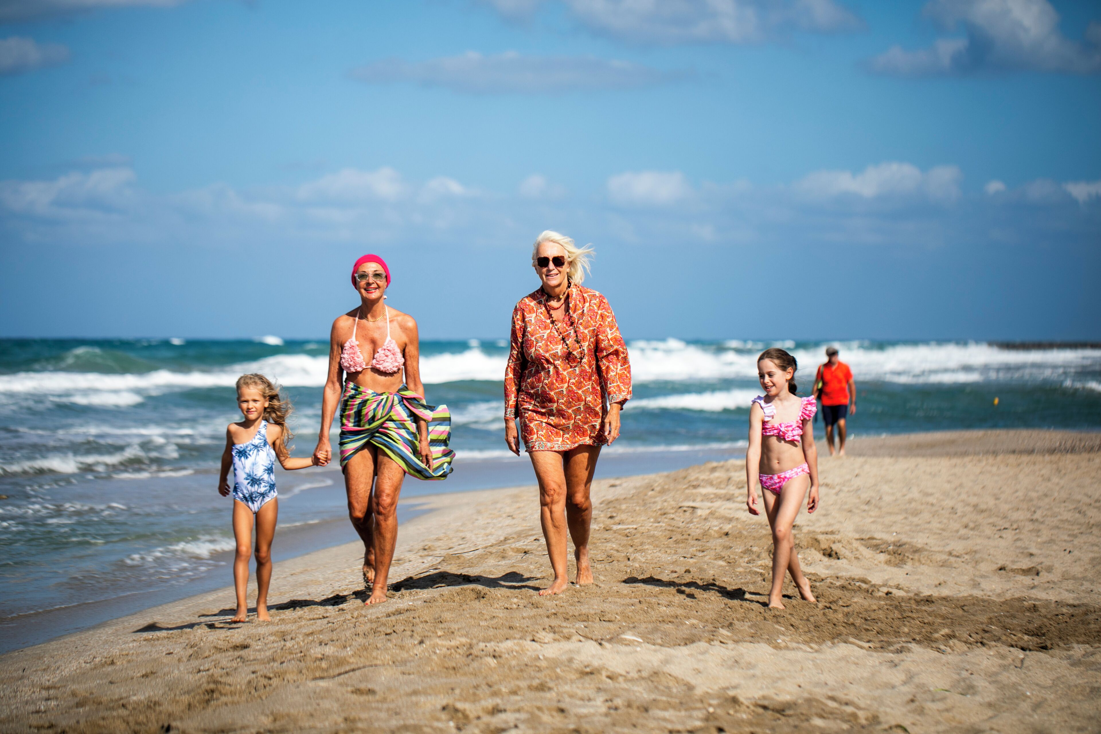 A beach scene with people walking along the shore.
