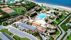 Vista aérea de un resort con piscina, canchas de tenis y una playa.