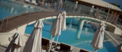 A pool area with lounge chairs and umbrellas.