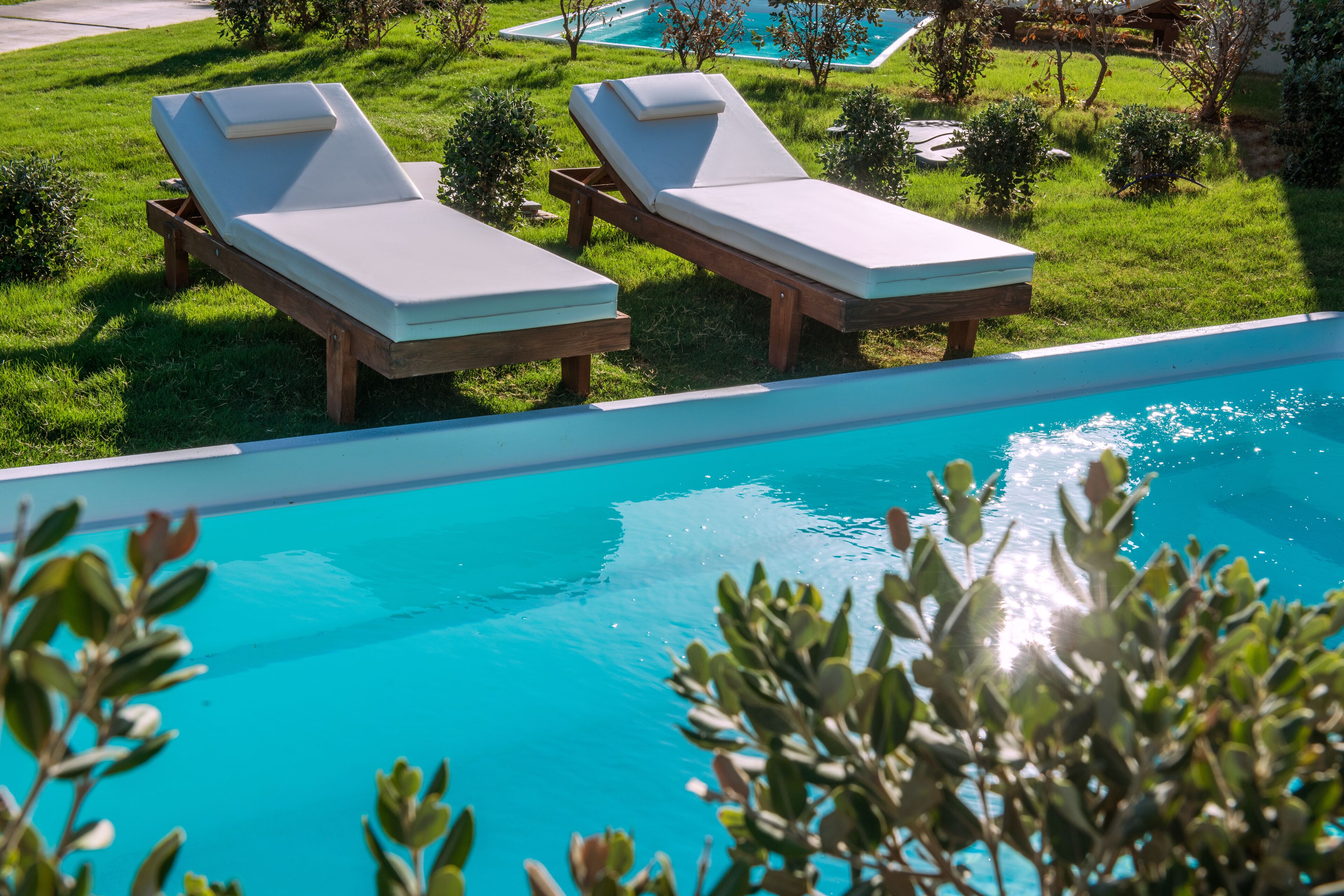 Un espace aménagé au bord de la piscine, avec deux chaises longues et une piscine à l’eau d’un bleu cristallin.