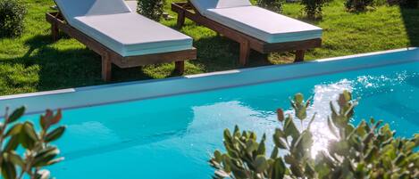Un espace aménagé au bord de la piscine, avec deux chaises longues et une piscine à l’eau d’un bleu cristallin.