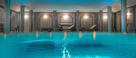 An indoor swimming pool with clear water, tiled walls, and a skylight.