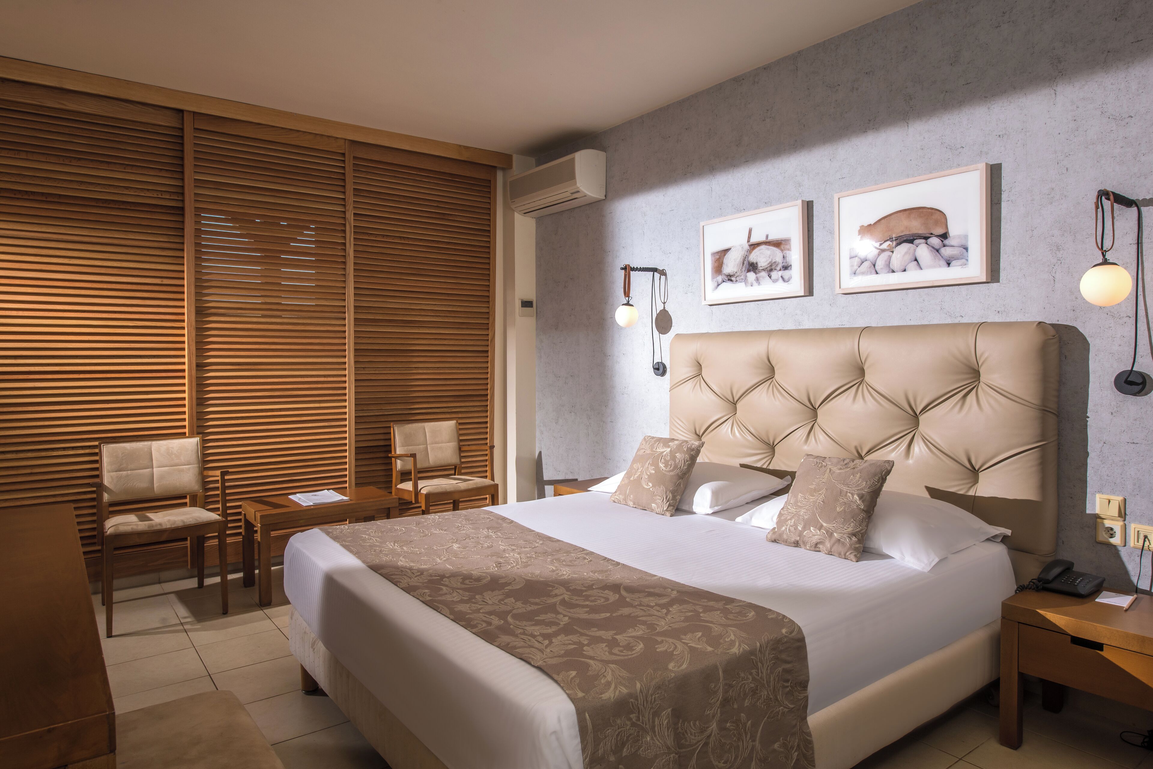 Een hotelkamer met een groot bed, een houten bureau, een stoel en een nachtkastje.
