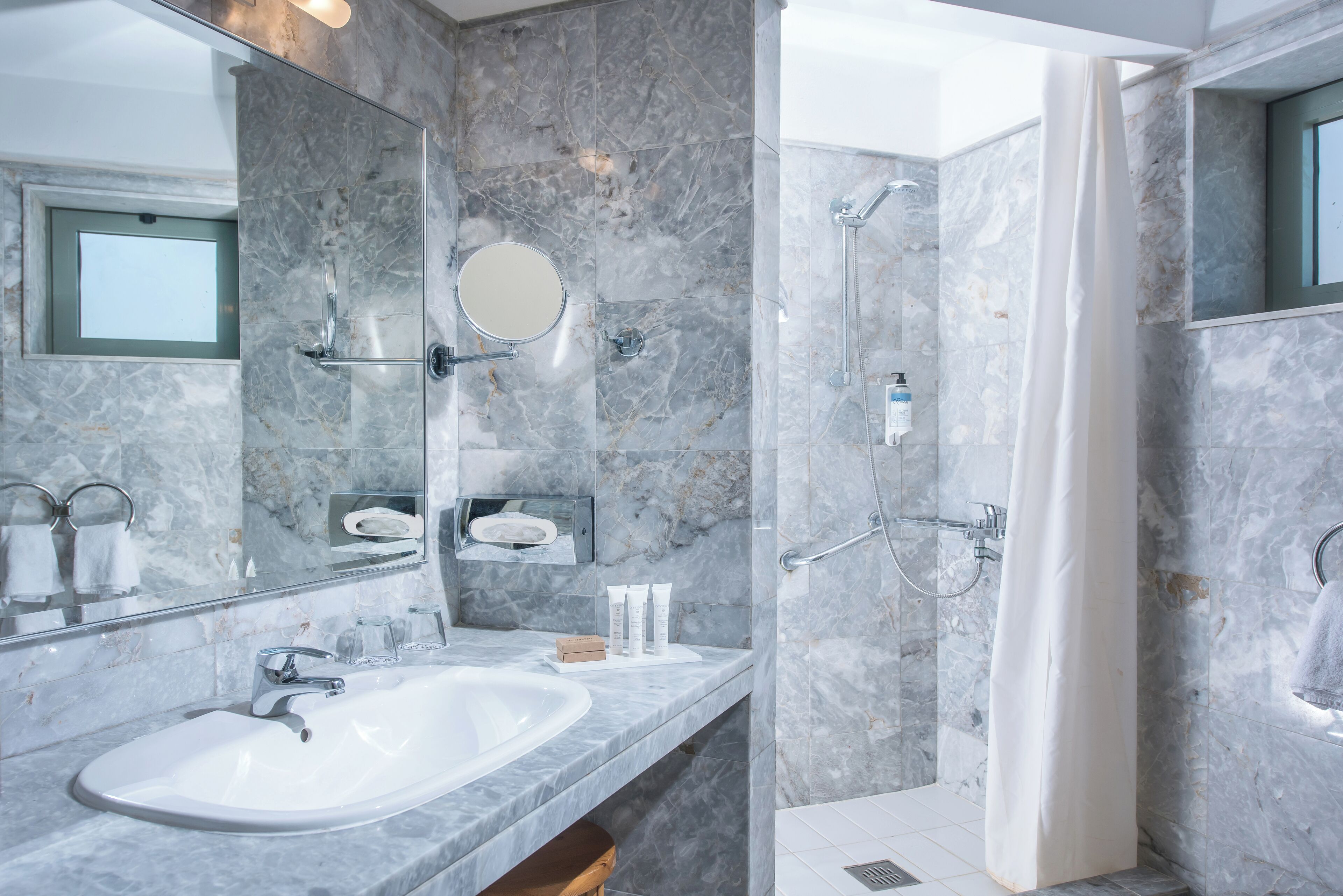 Une salle de bain moderne avec un grand miroir, un lavabo et un espace douche.