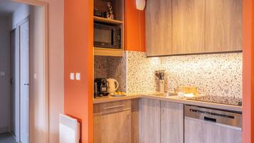 A compact kitchen with wooden cabinets, a microwave, a coffee maker, and a dishwasher.