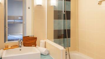 A bathroom with a sink, mirror, shower, and a towel rack.
