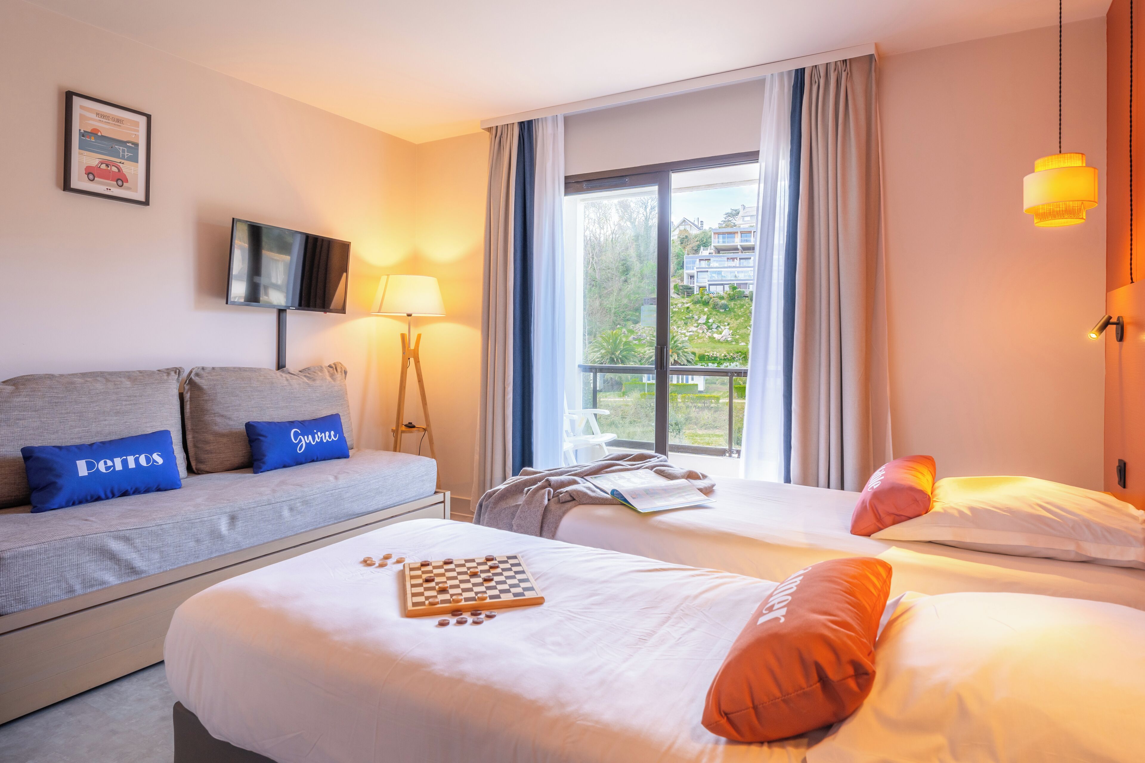 A hotel room with two beds, a sofa, a TV, and a window with a view.