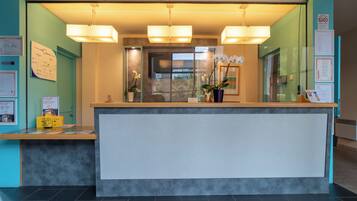 A reception desk with a counter, two pendant lights, and a potted orchid.