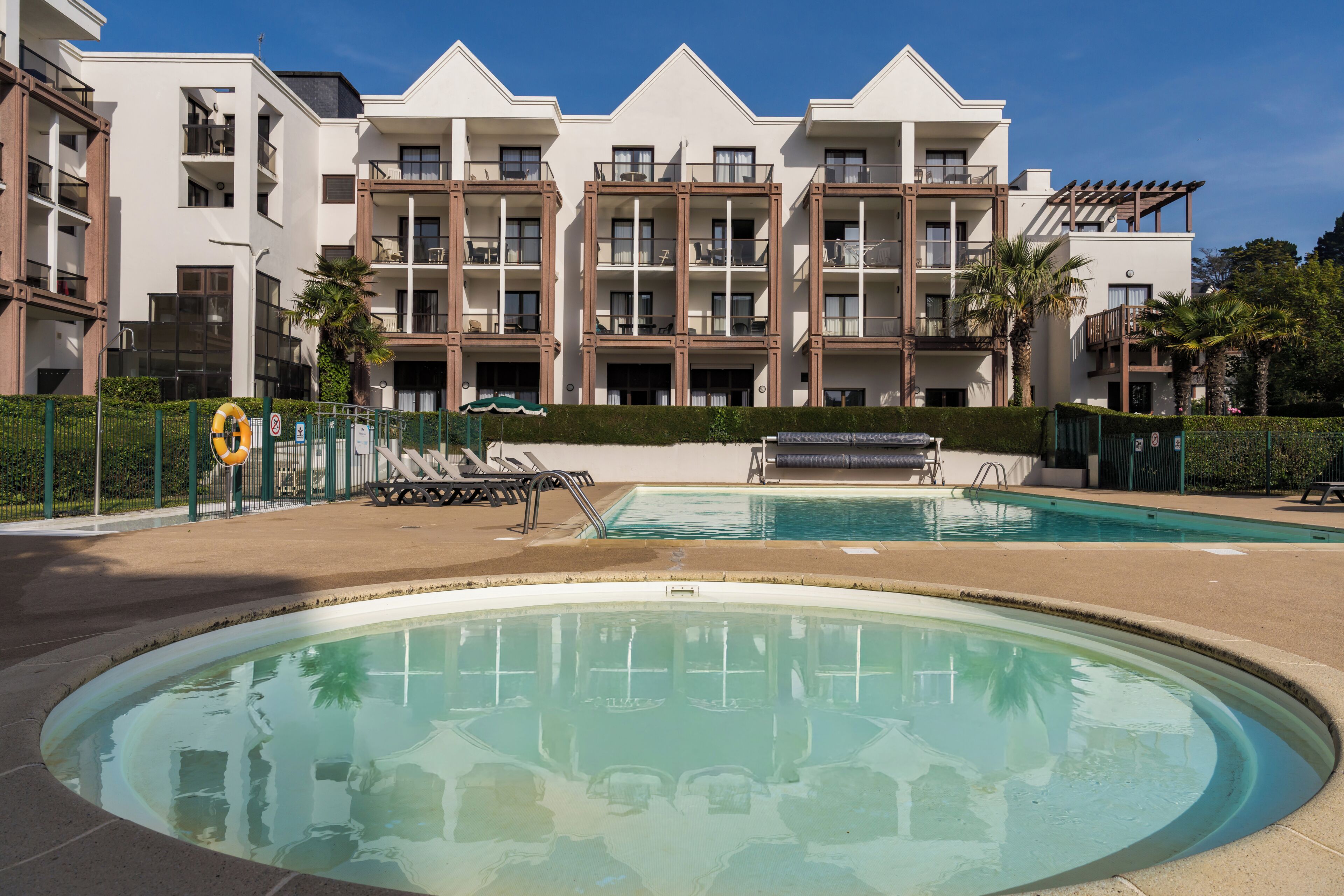 Ein Hotel mit Pool, mehreren Balkonen und blauem Himmel.