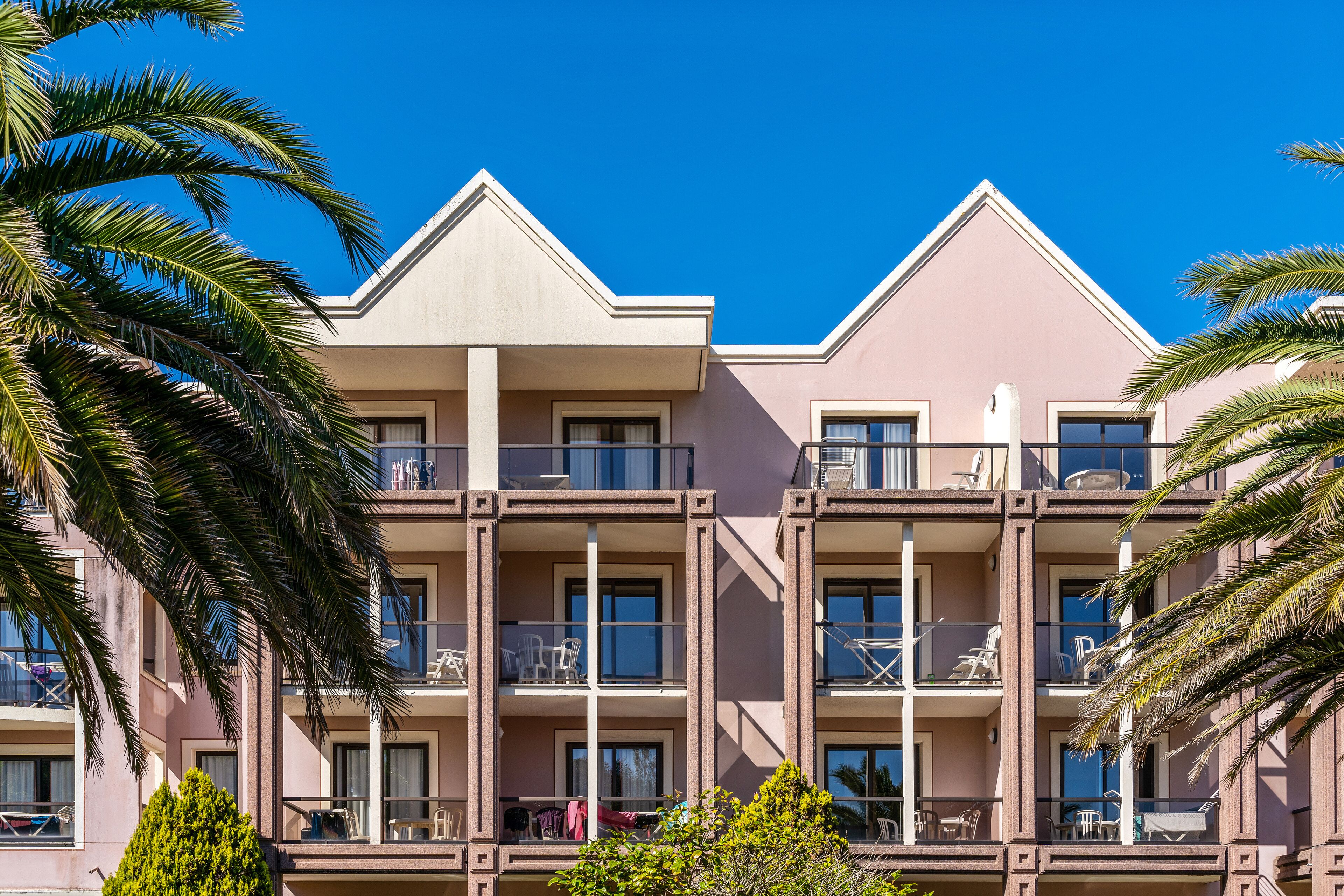 A multi-story hotel with balconies, large windows, and a clear blue sky.
