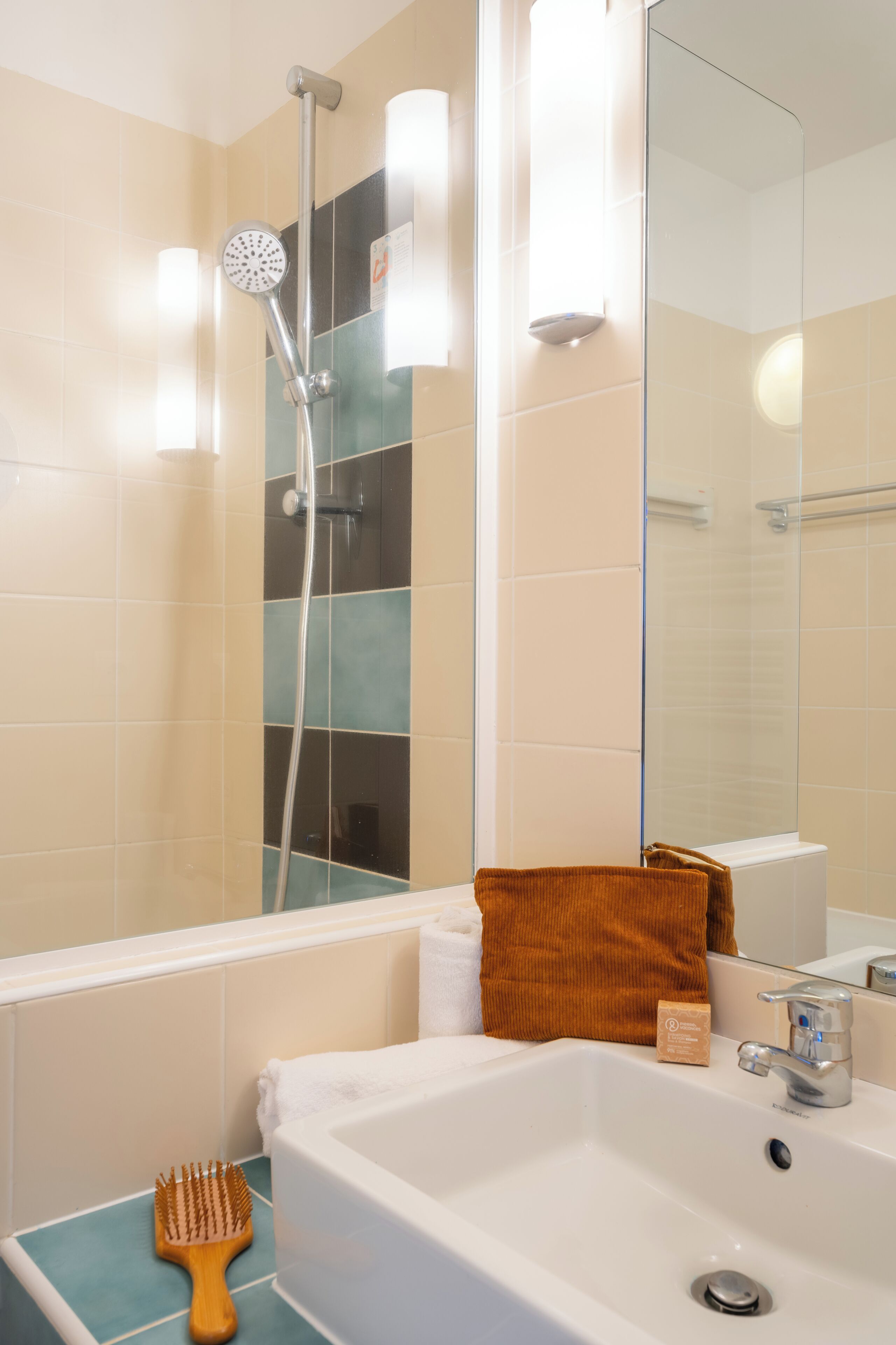 Une salle de bain avec une douche, un lavabo, un miroir et une serviette.