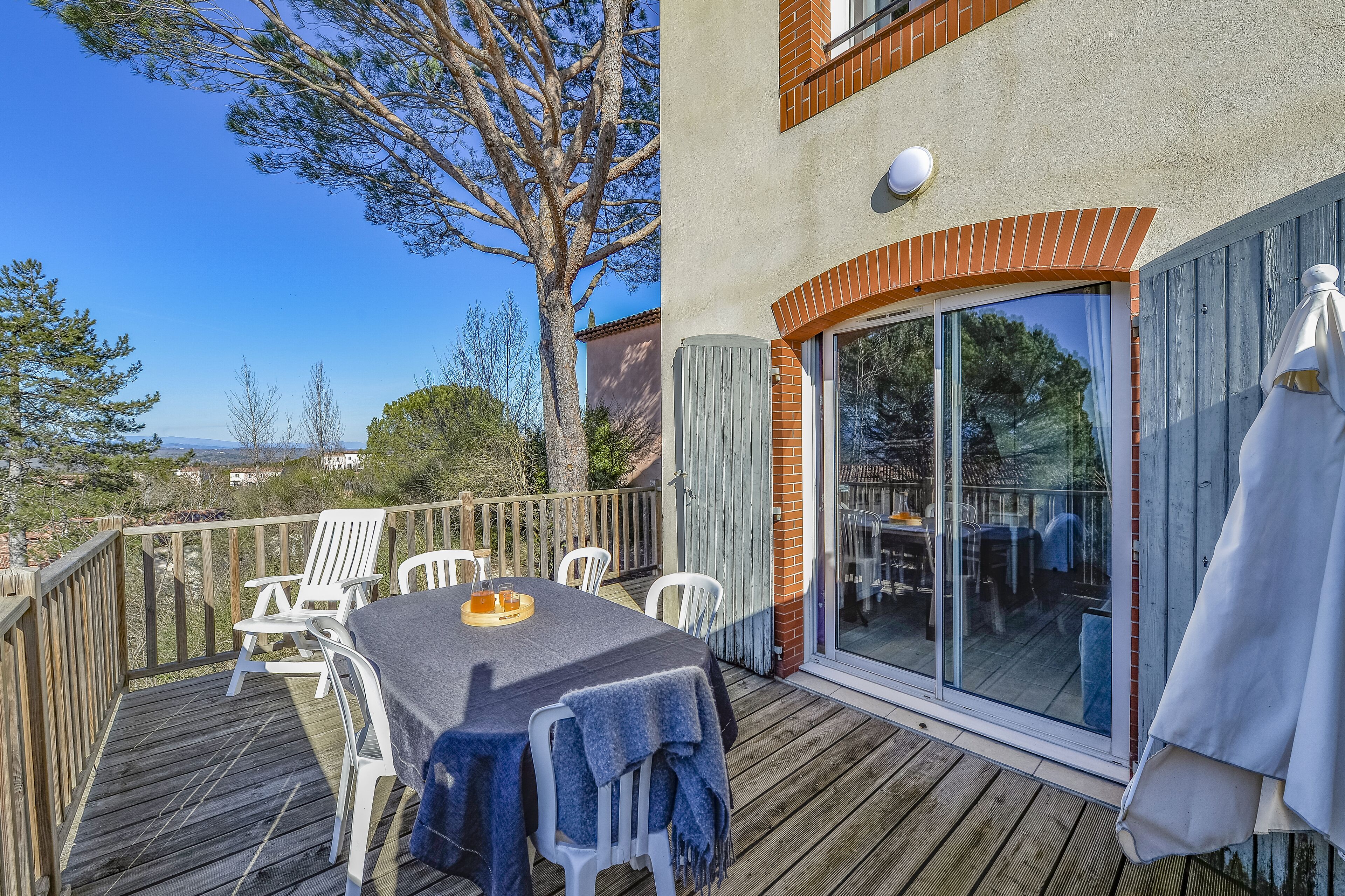 Una terraza con mesa y sillas, una puerta corrediza de vidrio y vistas al paisaje.